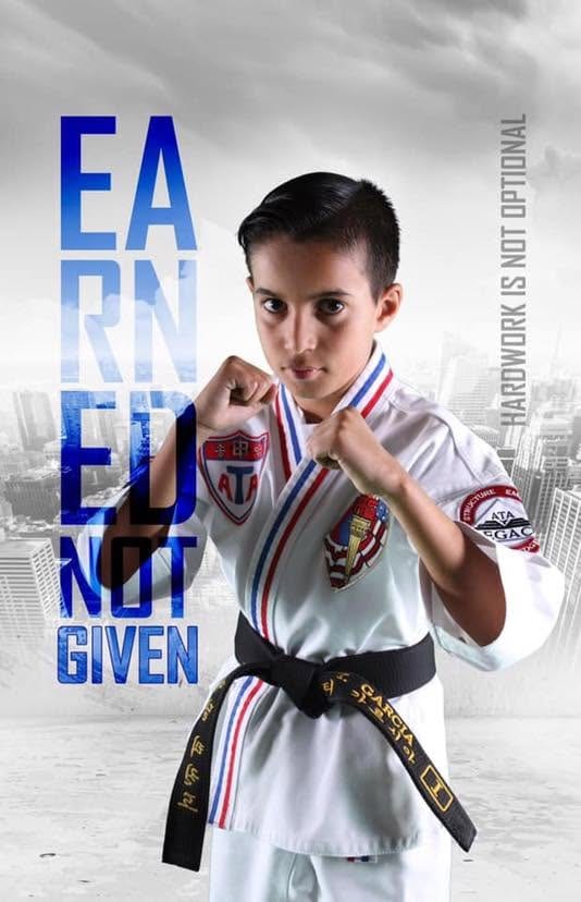 Martial artist in a white uniform with an 'Earned Not Given' graphic